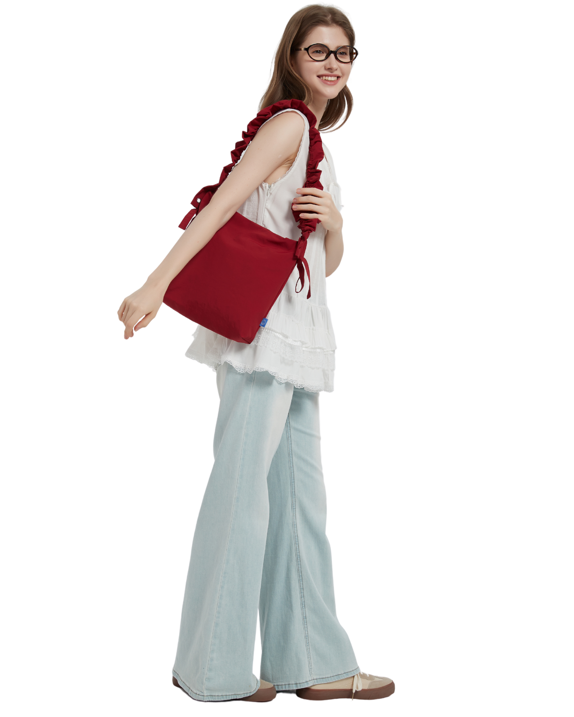 The petal bag in apple red as shown when it is shoulder carried on a model