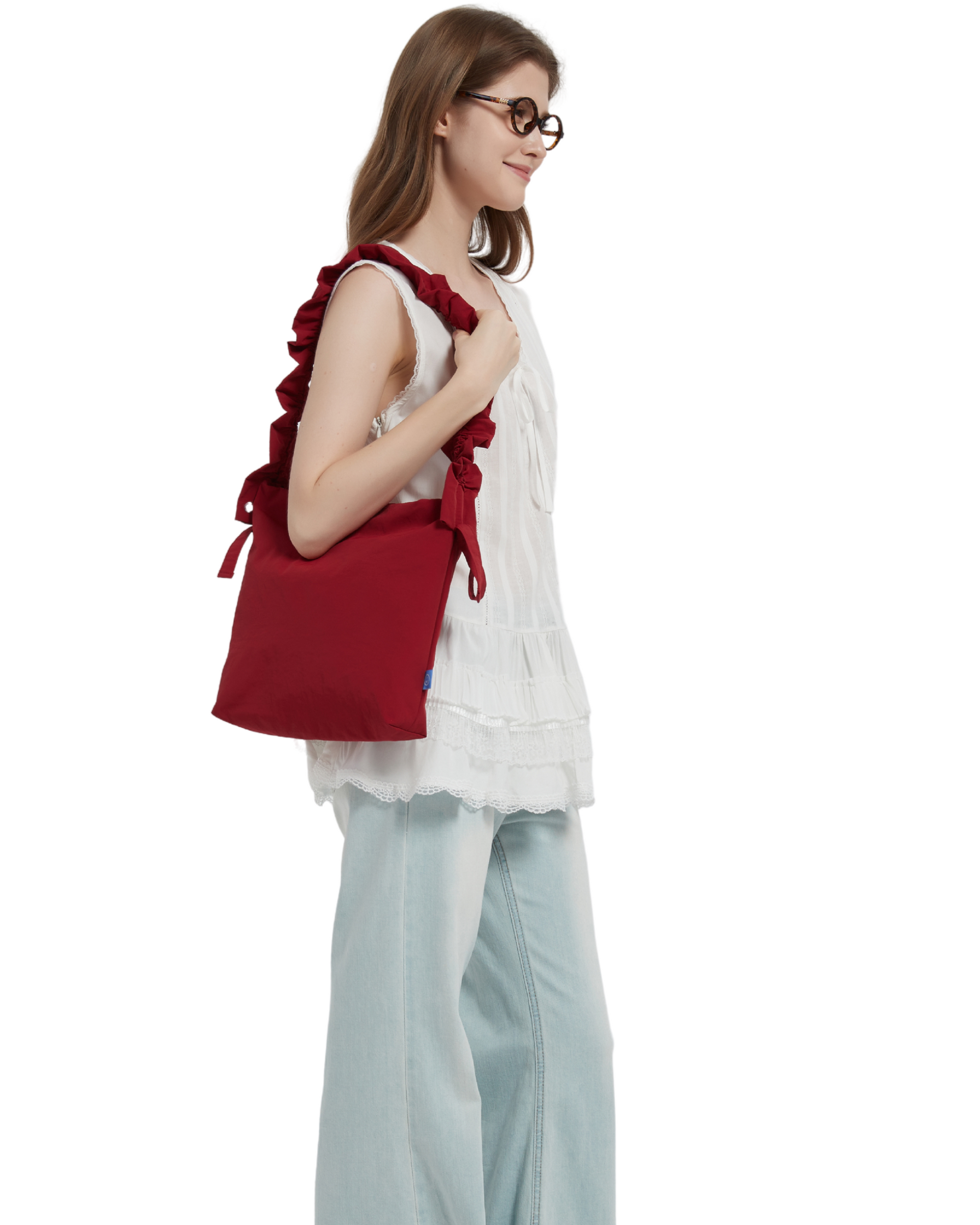 The petal bag in apple red as shown when it is shoulder carried on a model