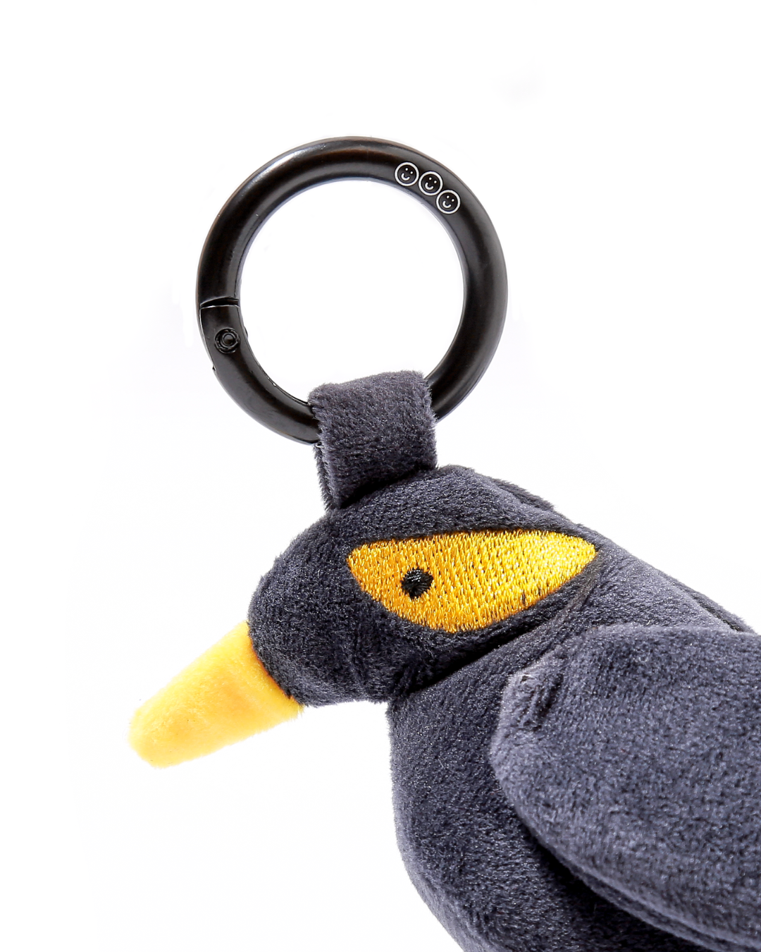 Plushie mynah bird with a black carabiner ring on a white background